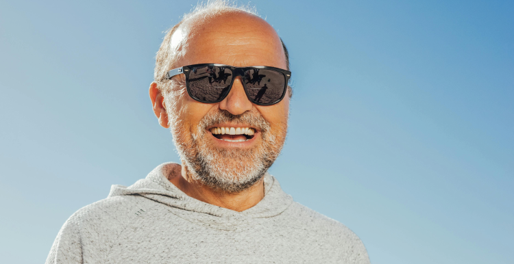 Older man in sunglasses smiling to camera on a sunny day