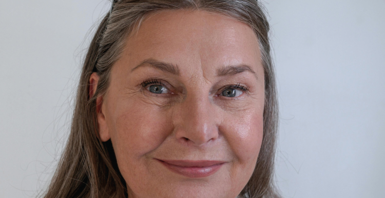 Woman over 55 with glasses on her head smiling to camera