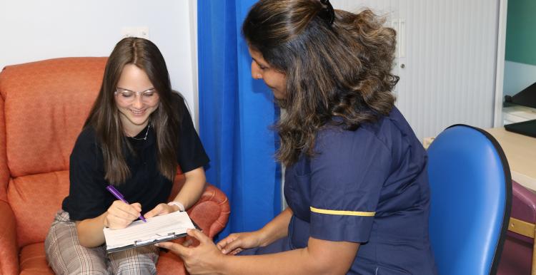 Medical research nurse filling out a form with a patient