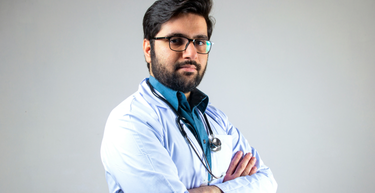 Medical professional in unform, arms folded, looks to camera