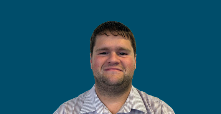 Photo of employee Ben smiling to camera against a dark blue background