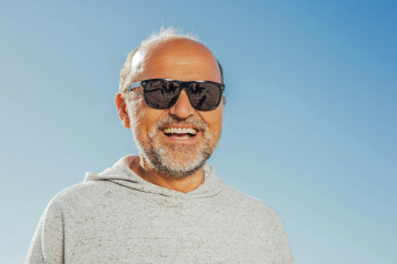 Older man in sunglasses smiling to camera on a sunny day 