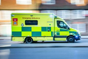 Ambulance driving quickly along a road