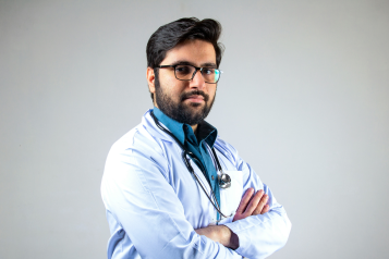 Medical professional in unform, arms folded, looks to camera