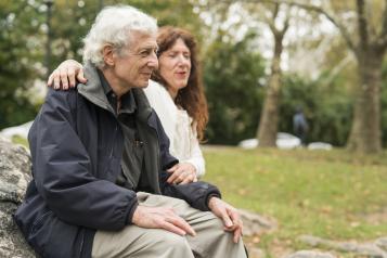 Elderly person sitting on a bench with a friend