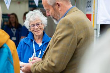 Woman from Healthwatch Cornwall smiling with a man filling in a form