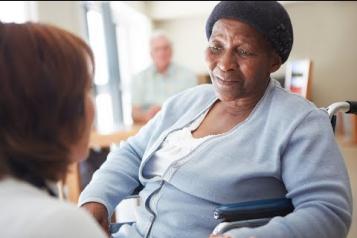 Elderly woman in a nursing home being spoken to by a nurse