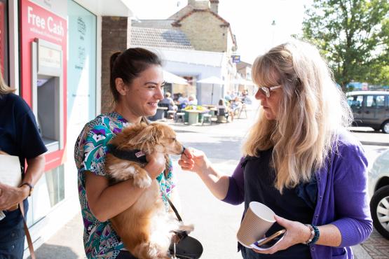 2 people having a chat with a dog.