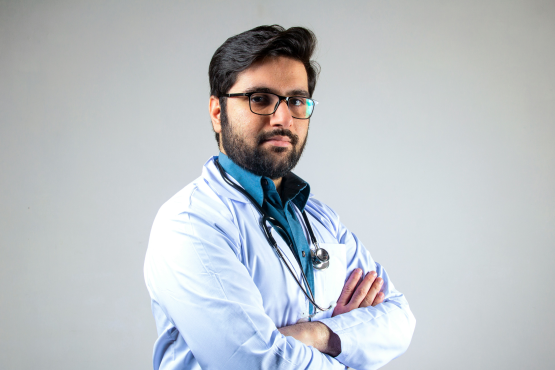 Medical professional in unform, arms folded, looks to camera