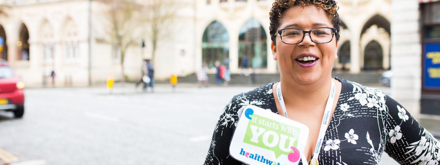 Woman holding 'It starts with you' sign outside