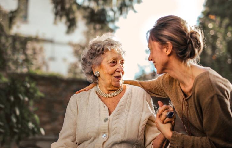 Two women are in a garden smiling as they speak to each other
